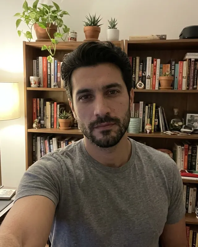 Kitaplık önünde çekilmiş gündelik bir erkek selfie'si.